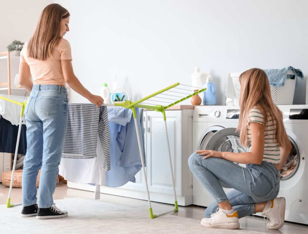 two teen girls in a laundry room doing clothes