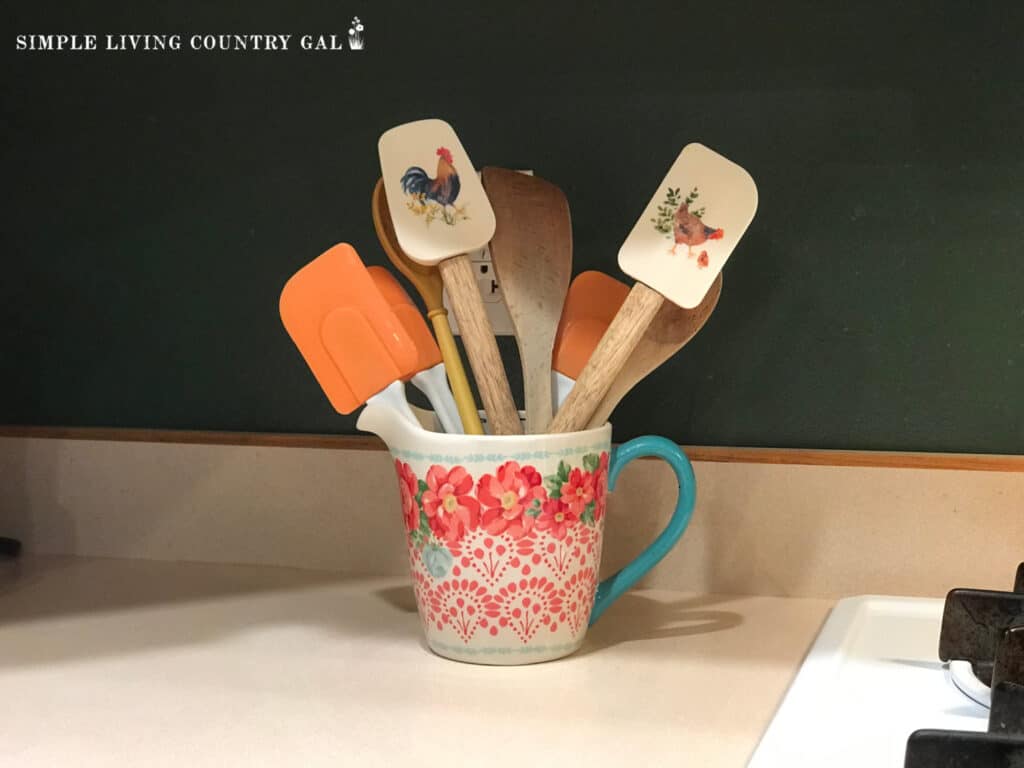 a crock in a simple kitchen holding cooking tools