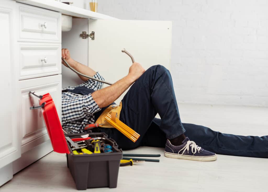 man working under a sink making repairs