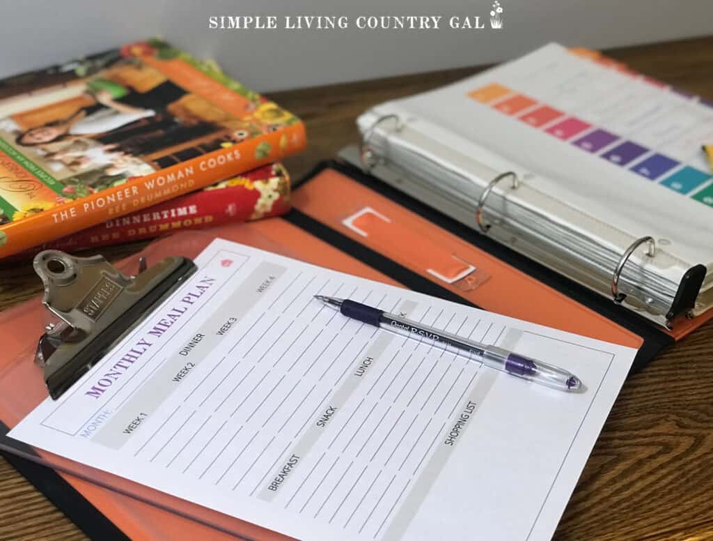 a meal planning page sitting next to an open binder and recipe books