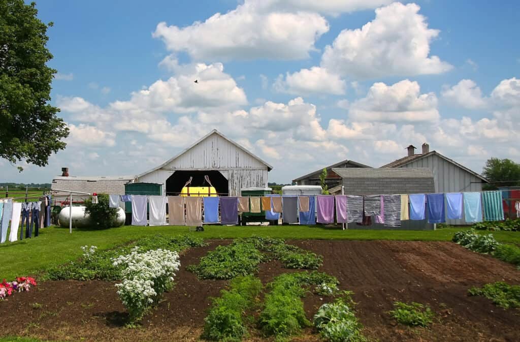 clothes hanging on the line at an amish home near to a large vegetable garden