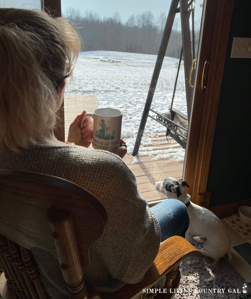 woman looking out at the snow with a cup in hand