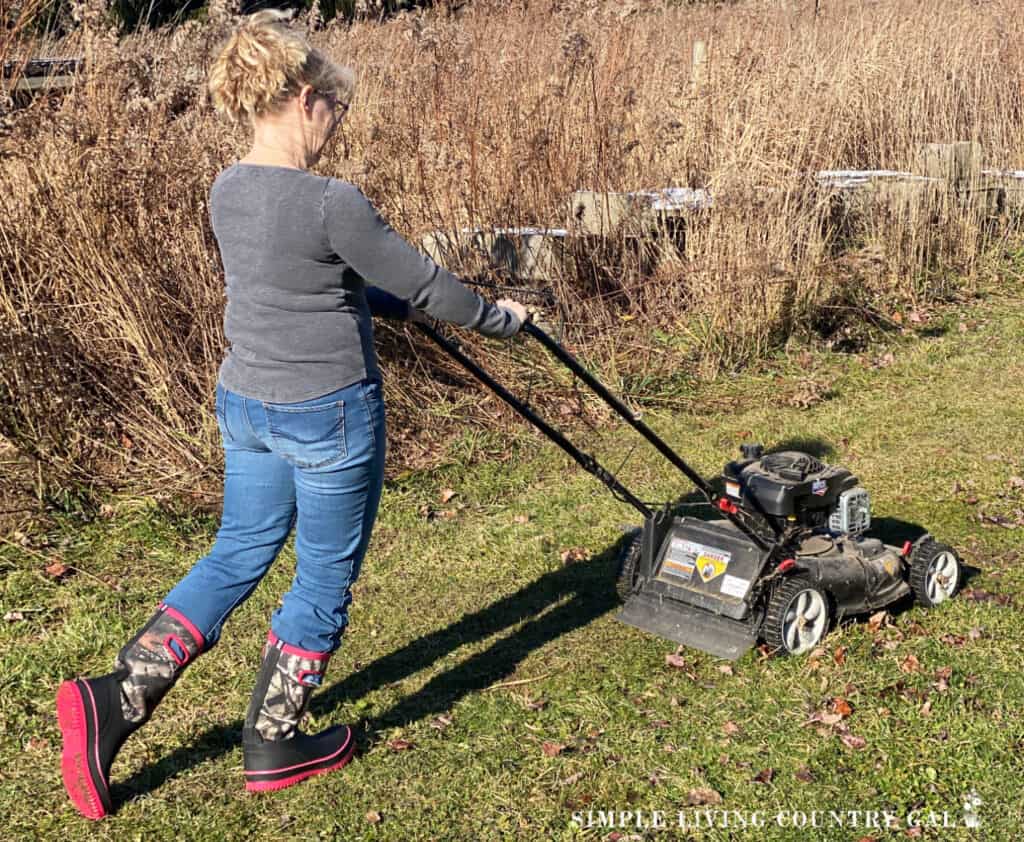 a woman mowing down an area for a backyard garden from scratch