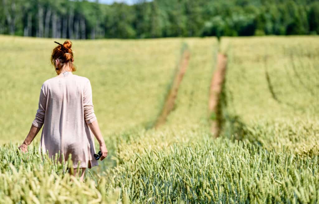 a woman walking in a field of a honmestead