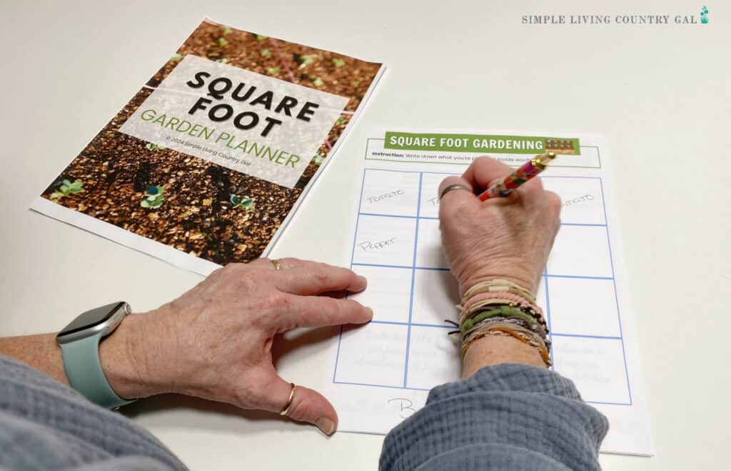 hands writing out a garden plan on a grid sheet of paper