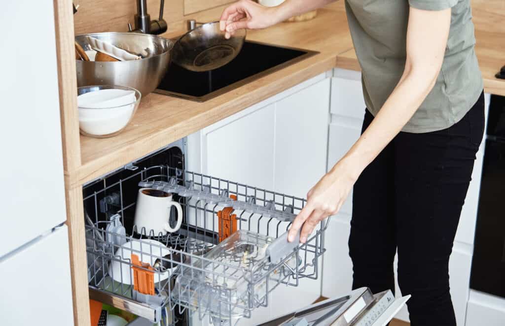 a woman loading a dishwasher after a meal 