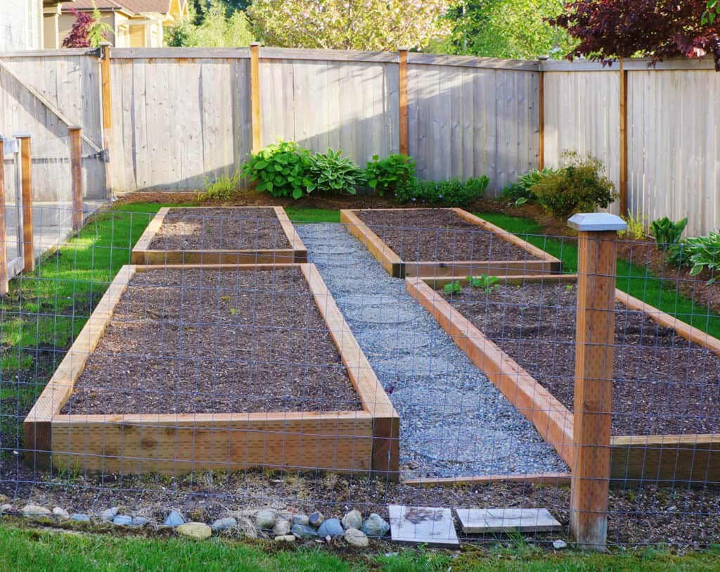 a fenced in vegetable garden of raised beds