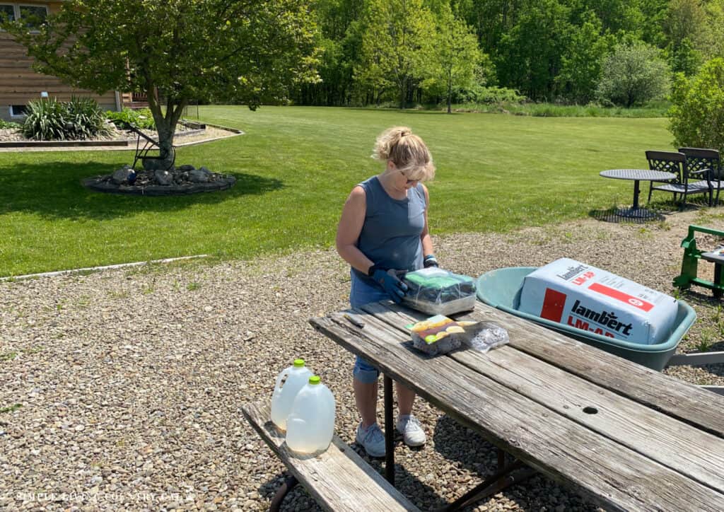 a woman preparing to plant potatoes in grow bags by a picnic table