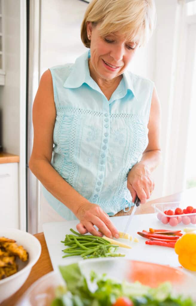 an empty nester woman chopping garden vegetables in a kitchen