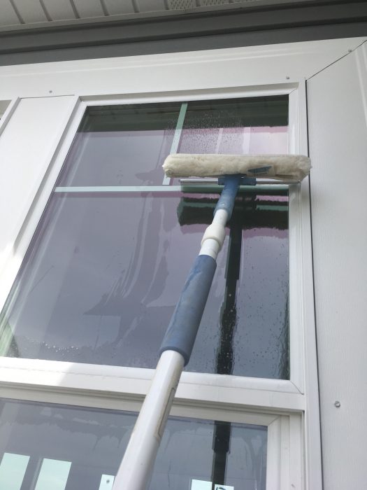 outdoor glass window being cleaned with a mop