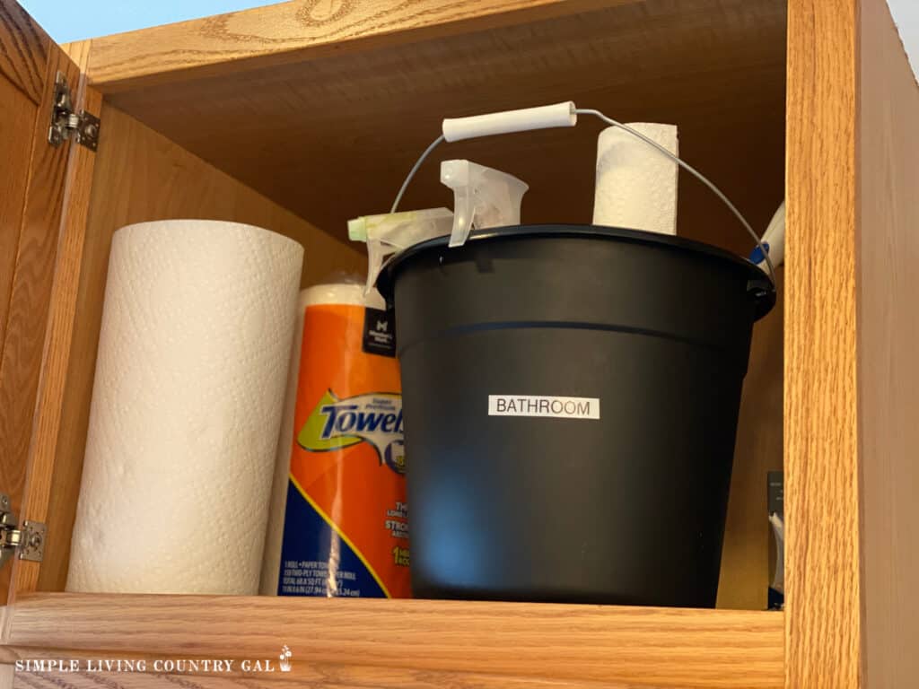 a black bucket in a bathroom filled with cleaners