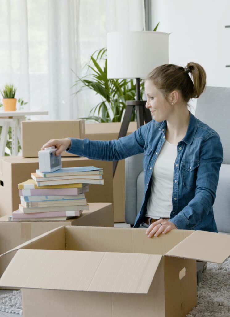 a woman putting clutter into boxes while sitting in a family room