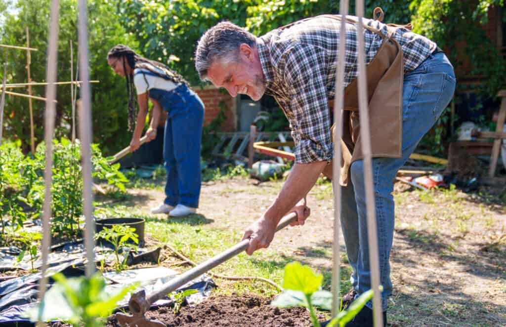 an older man and a younger woman working in a community garden