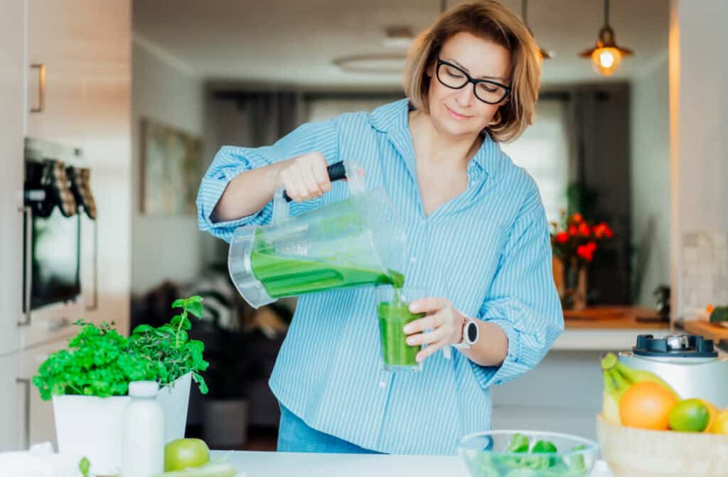 woman mixing a smoothie with fresh basil growing nearby