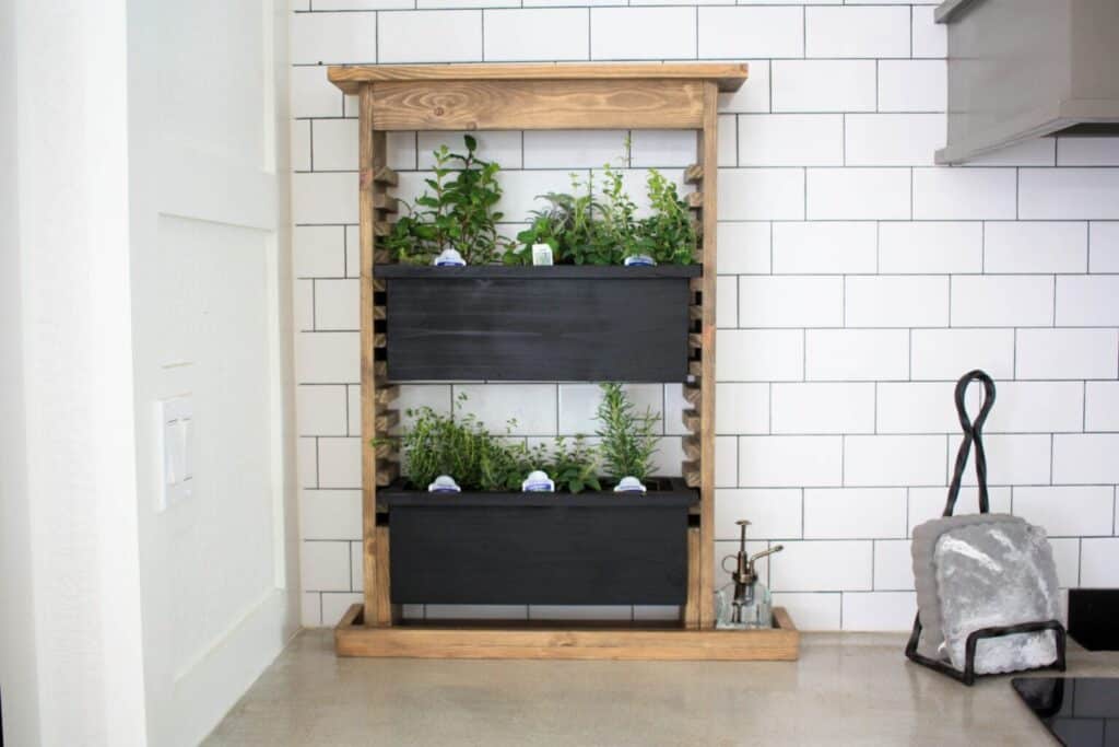 indoor herb garden using a removable planter system, with a wooden frame with two large black planter boxes