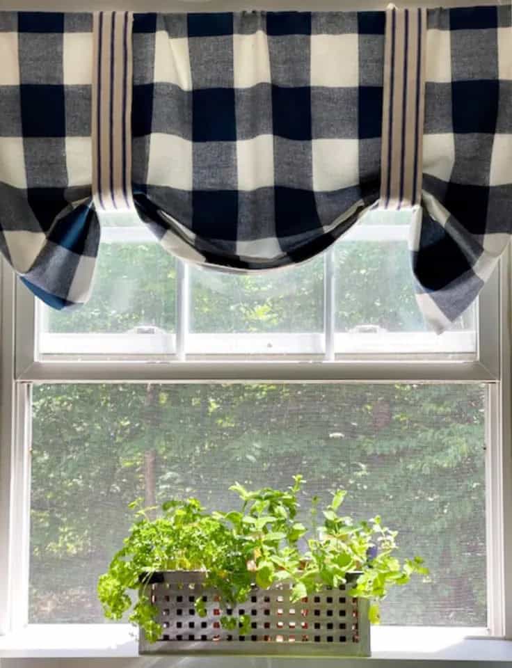 windowsill herb garden, the herbs are planted in a rectangular metal container with perforations