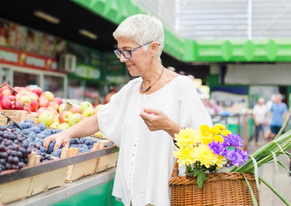 a midlife woman buying fresh fruit at a farmers market