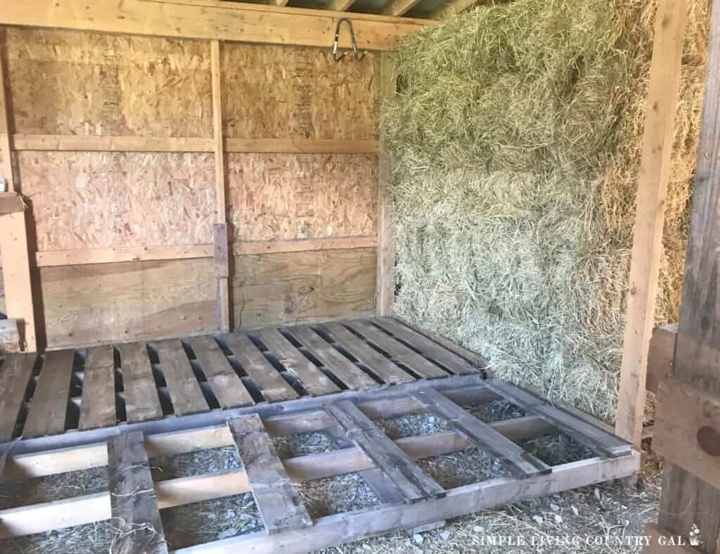 hay stored in a barn in front of a section of empty pallets