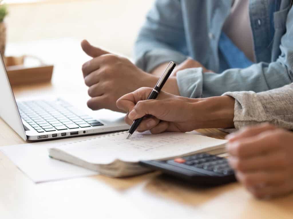 a couple's hands with a calculator and a laptop 