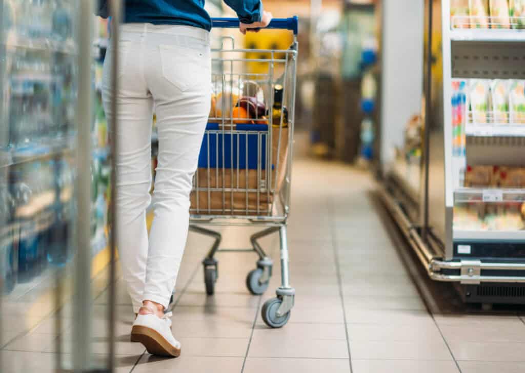 a woman in white pants pushing a cart in a grocery store