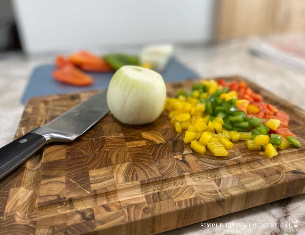 diced peppers with a whole onion on a cutting board