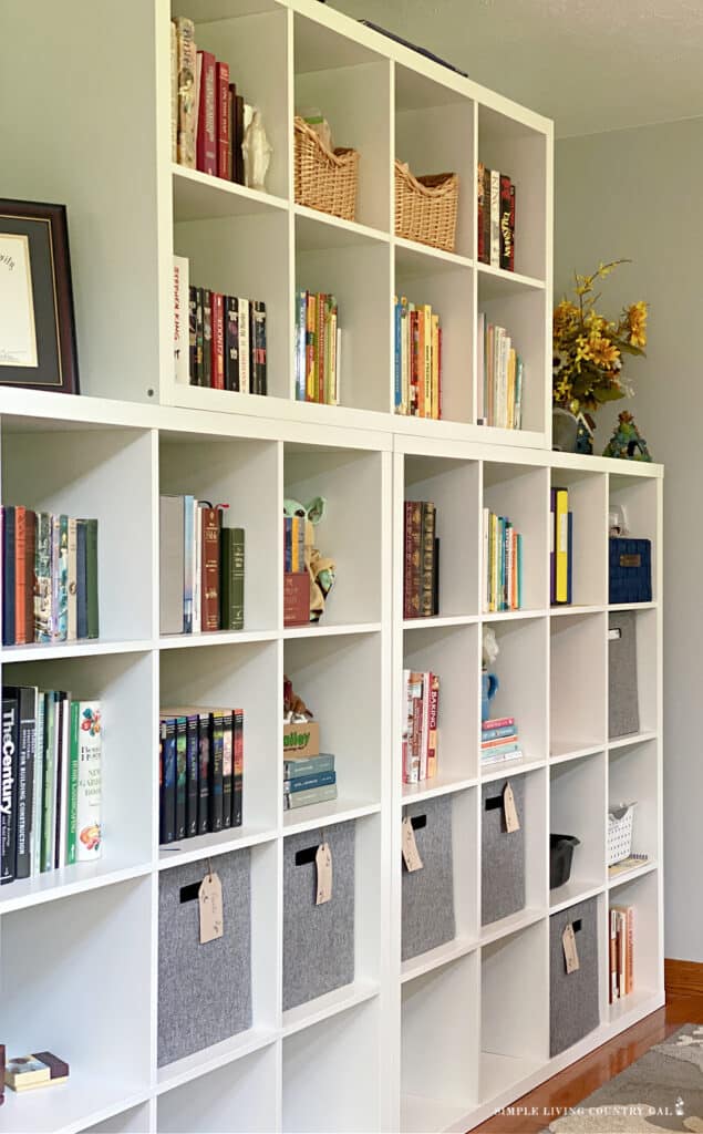 white bookshelves filled with books and baskets in a home library