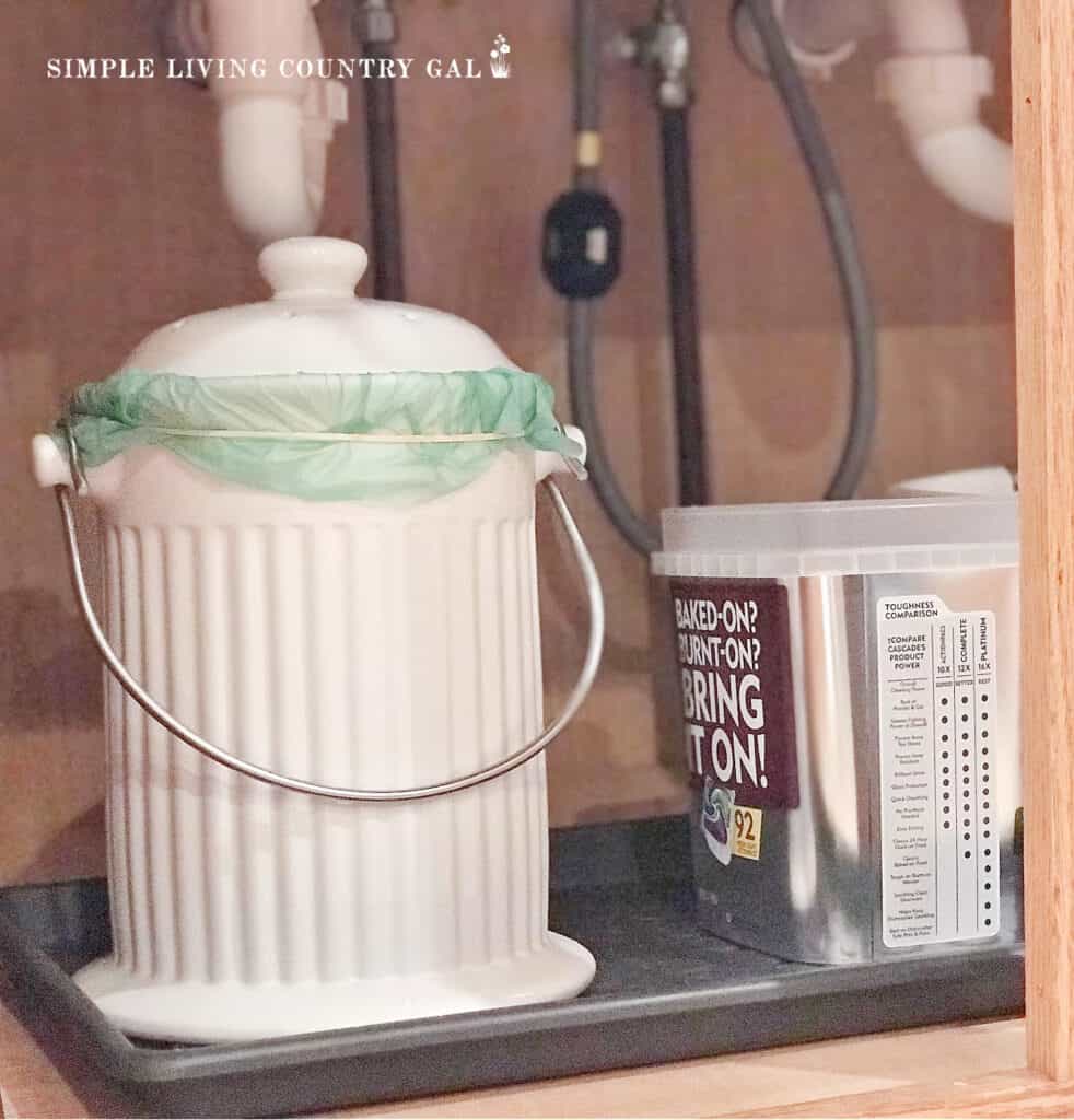 a white compost bucket under a sink in a modern homesteading kitchen