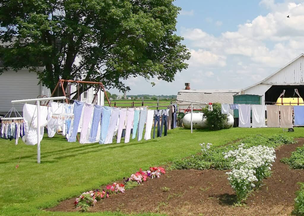 an amish home with clothes drying on a line next to a garden