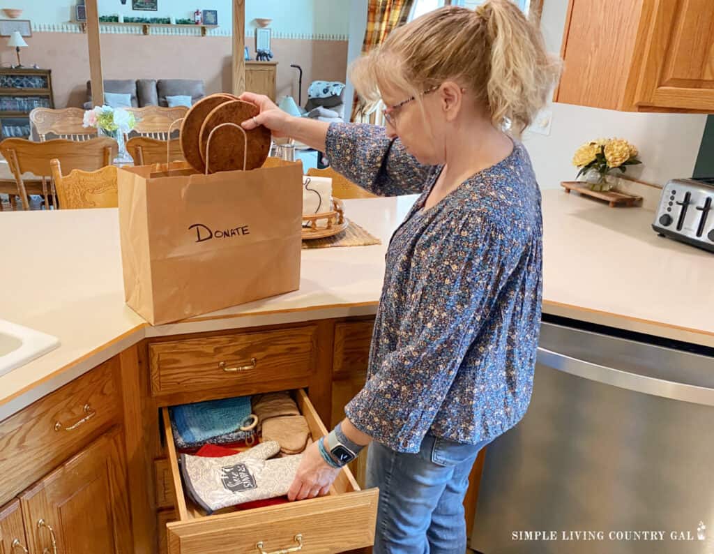 a woman decluttering potholders in a kitchen