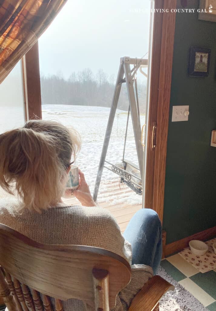 a woman drinking coffee in a chair looking out the window