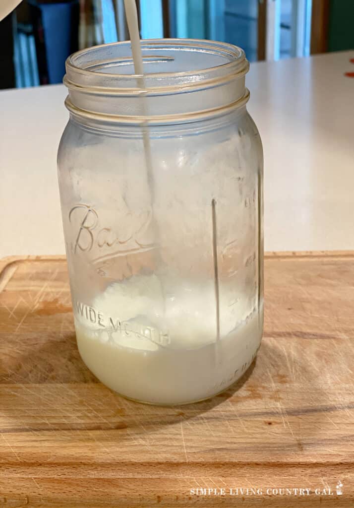 fresh goat milk being poured into a jar