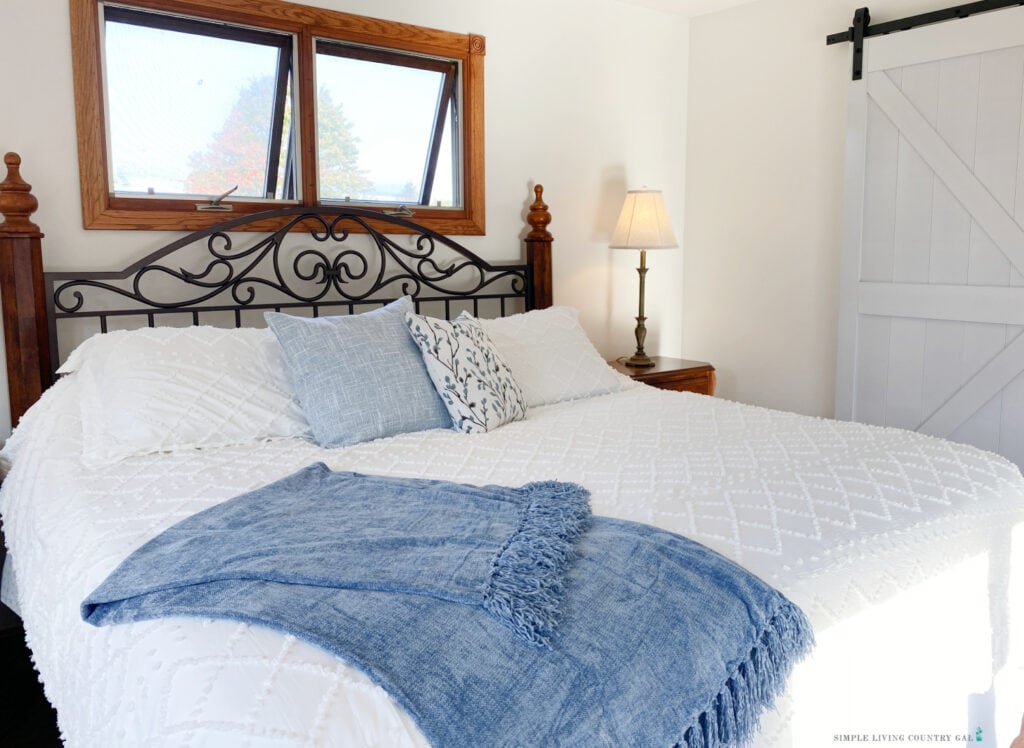 a bed with a white comforter, blue pillows, and a cozy blue blanket