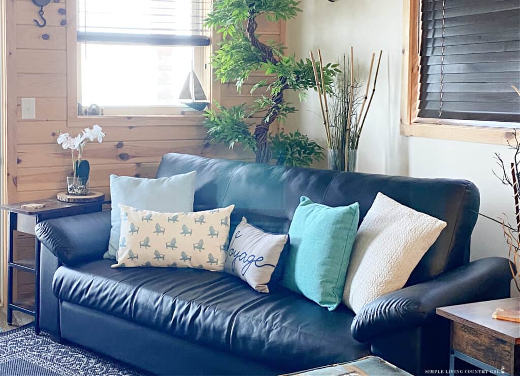 a cozy black couch covered in light colored throw pillows