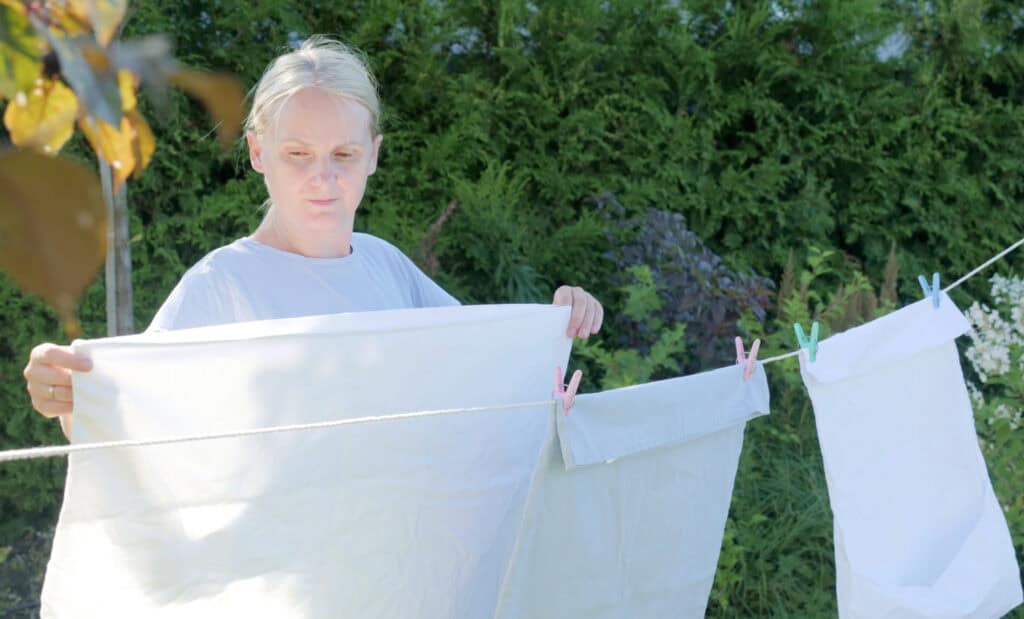 a midlife women hanging towels on a line with clothespins