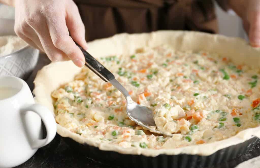 a woman making a casserole with leftovers in her kitchen