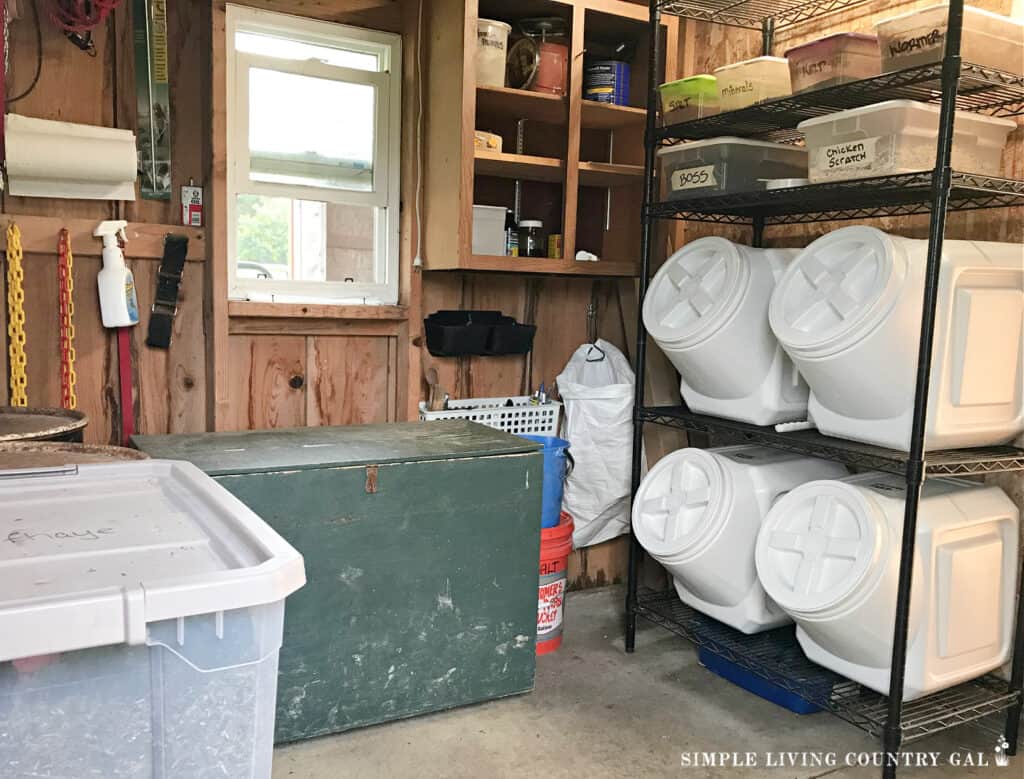a feed room in a barn filled with containers, totes, shelving and tack box