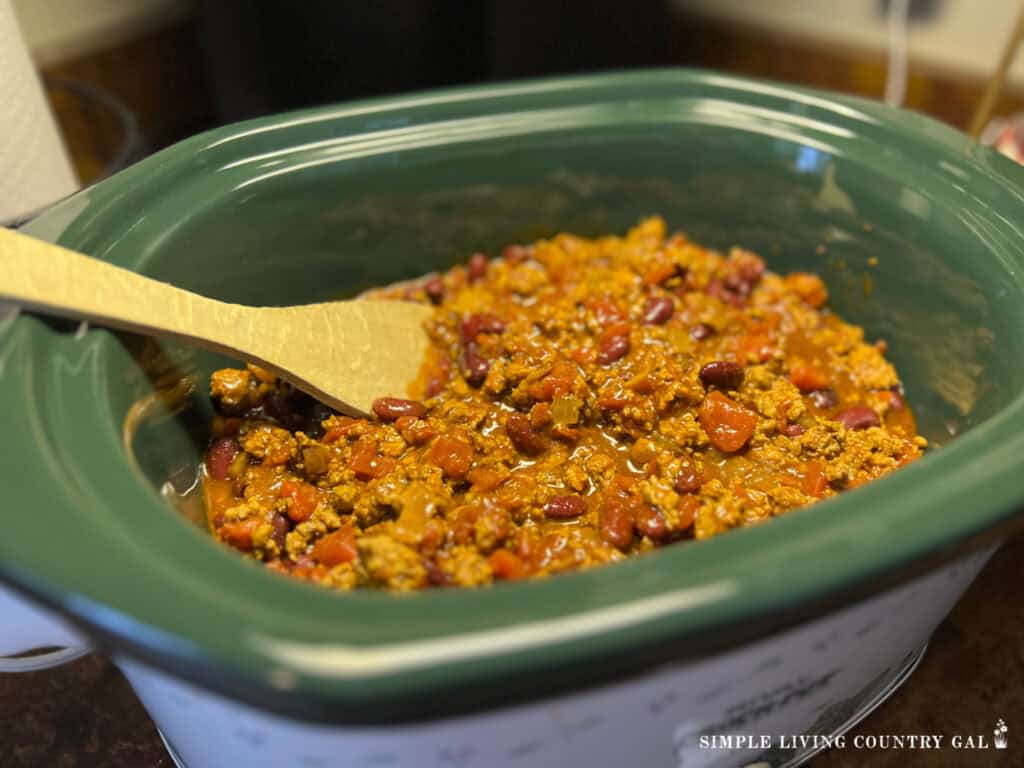 chili in a crock pot with a wood spoon
