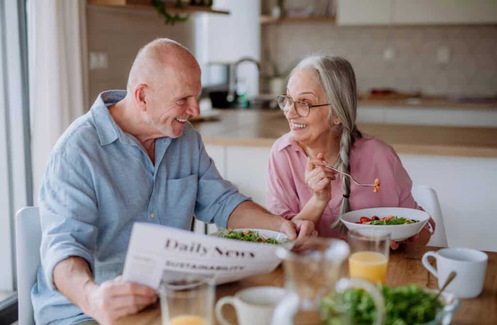 happy couple eating a from scratch meal at a table in kitchen