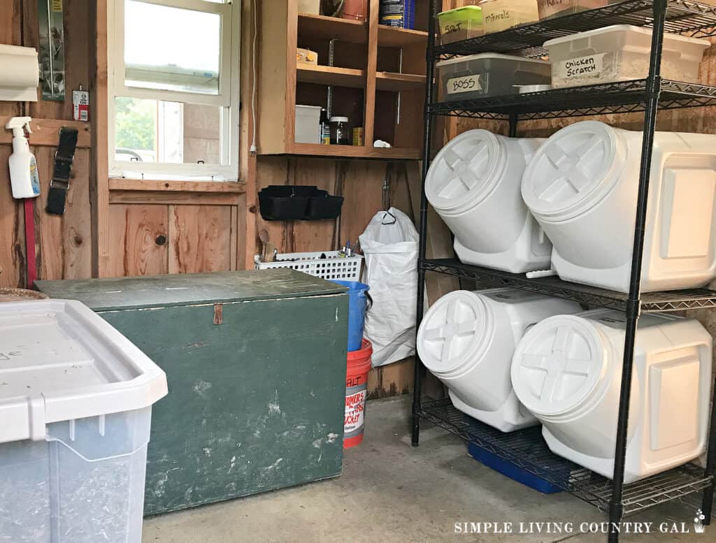 a feed room in a barn filled with containers, totes, shelving and tack box