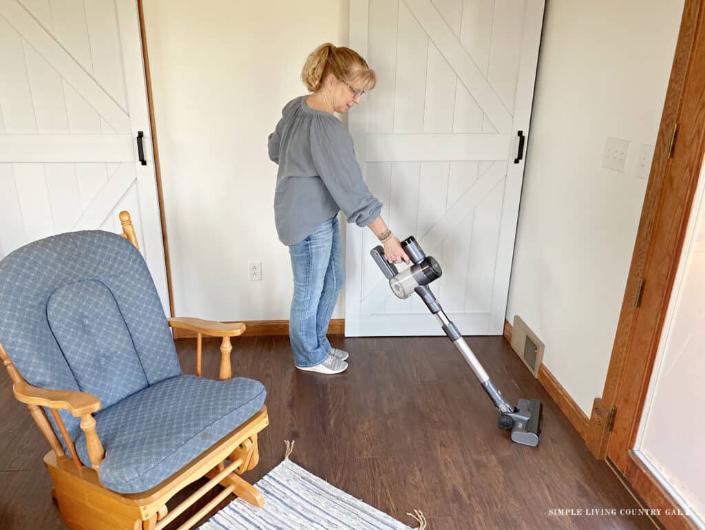 a woman vacuuming a floor near to a chair